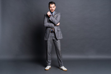 Full length portrait of a fashion male model over grey background. Looking at camera.