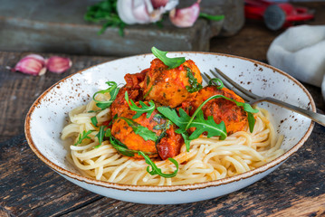 Spaghetti with tuna balls in spicy tomato sauce and rocket