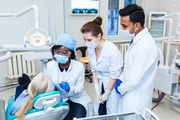 A multinational group of dentists examines x-rays in the presence of a patient. Practice at a...