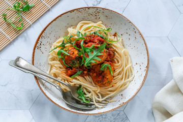 Spaghetti with tuna balls in spicy tomato sauce and rocket