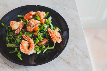 salad with shrimps and tomatoes on a black plate