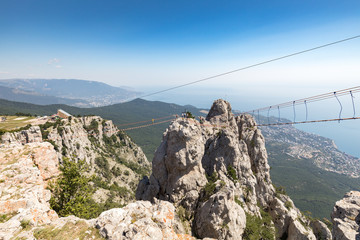 Aerial view of rock with a rope bridge on the Mount Ai-Petri in Crimea, Russia. Ai-Petri is one of the highest mountains in Crimea and tourist attraction. Hanging bridge on Ai-Petri over the abyss. - 245687246