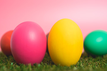 Colorful Easter eggs clean on grass and pink background