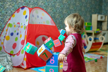 child little girl play with wooden cube toys at home or kindergarten