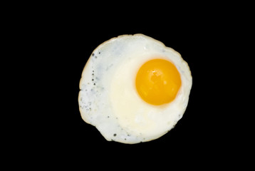 Top view of a sunny side up fried egg isolated on a black background in close-up