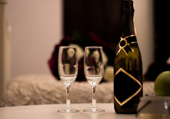 Two wineglass for champagne in cozy room for valentine day, light candle