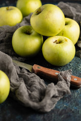 green apples on a textured dark background with a knife for slicing
