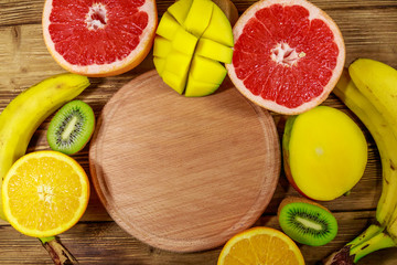 Assortment of tropical fruits on wooden table. Still life with bananas, mango, oranges, grapefruit and kiwi fruits