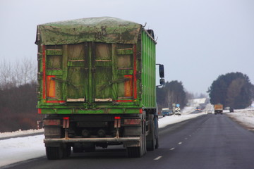 Heavy semi trailer garbage truck with green awning open top container on winter road - transportation, logistics