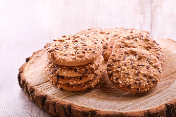 Cookies of sesame seeds, sunflower seeds and other spices on a wooden plate. Bright key