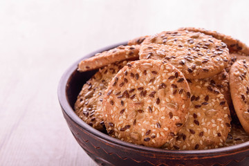 Cookies of sesame seeds, sunflower seeds and other spices on a wooden plate. Bright key