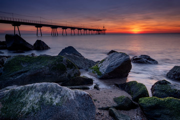 Sunrise in Oil bridge near Barcelona. Rocks and beach views