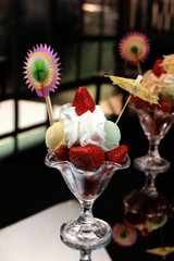 Copa con fresas naturales, dos bolas de helado, nata montada y dos adornos de papel.