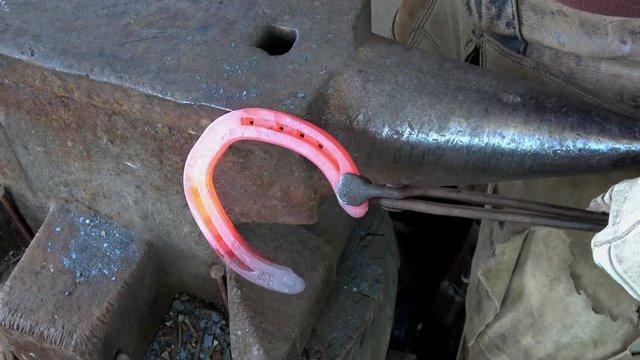 Schmiedearbeit, ein hei&szlig;es Hufeisen wird auf einem Amboss bearbeitet (geschlagen)