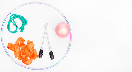 Accessories for rhythmic gymnastics ball, clubs, ribbon, rope lie on the floor. Black background