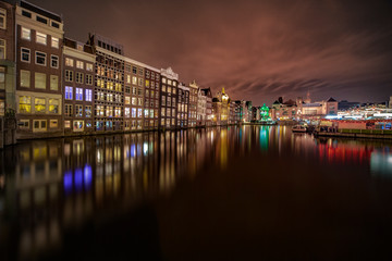 Fototapeta premium Iconic Amsterdam view with its canals and illuminated houses in front the train station, Netherlands
