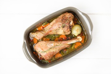 Top view of roasted turkey legs with vegetables in ceramic bowl