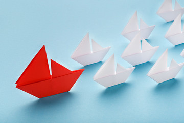 Red paper boat leading white ships, panorama