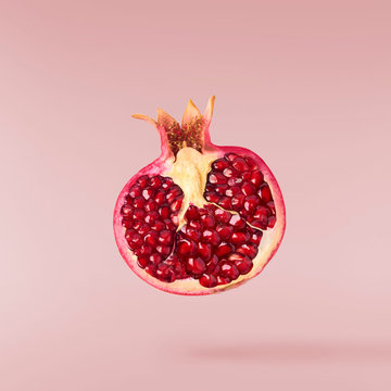 Flying in air fresh ripe pomegranate isolated on yellow background.