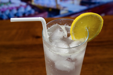 Tom Collins cocktail in highball glass with straw and decoreted slice of lime