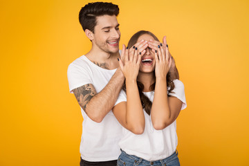 Handsome man covering woman's eyes standing behind her