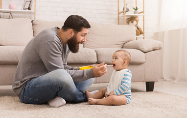 Father feeding his cute baby son at home