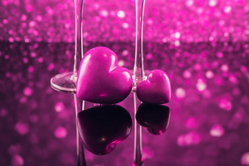 Two glasses of champagne with red heart shape bokeh on background.