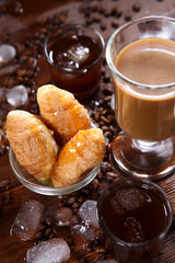Glass of coffee and milk top view and small croissants on wooden background. The concept of still life of coffee and ice.