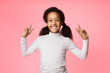 Funny girl showing peace signs on pink background