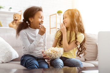 Best friends watching cartoon and eating popcorn