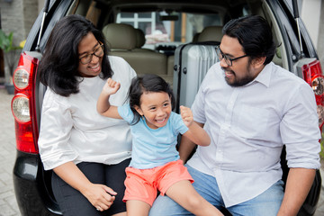 asian family with daughter sitting in car trunk 