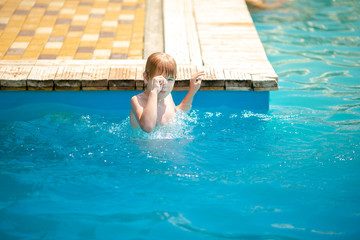 Little blonde child with strabismus in the blue swimming pool