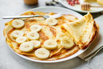 Food, dessert, pastries, pancake, pie. Tasty beautiful pancakes with banana and honey on a concrete background