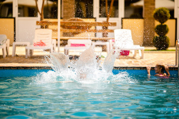 Little blonde girl in bright pink swimsuit having fun in the summer blue swimming pool