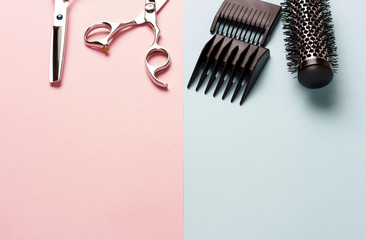 Scissors and comb on a pink and blue background, copy space