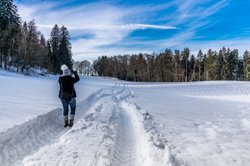 Fototapeta na wymiar Junge Frau fotografiert Landschaft beim Winterspaziergang