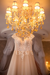 morning of the bride.details, wedding dress hanging on a beautiful chandelier.