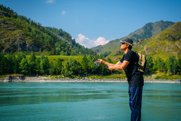 Fisherman on the mountain river at the nice summer day. Trout fly fishing in the mountain river with mountains in background