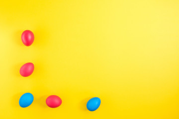 The frame of the creative layout of eggs painted red and blue colors on a yellow background