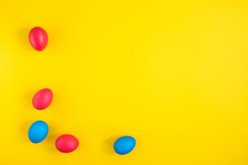 The frame of the creative layout of eggs painted red and blue colors on a yellow background