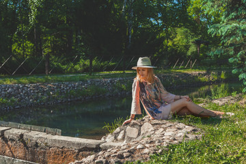 Girl in a picturesque park in the center of a large city in the summer. With a lagoon in the middle and green trees. In the atmosphere of the evening light