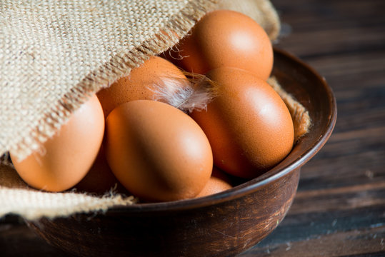 chicken eggs in a clay plate on a wooden table