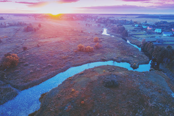 Magical sunset over the countryside. River on the meadow. Rural landscape in the evening. Aerial view