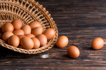 chicken eggs in a straw tray on an old wooden table