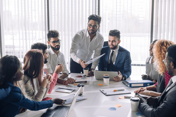 Young business team having a brainstorming session sitting grouped around the table and sharing new...