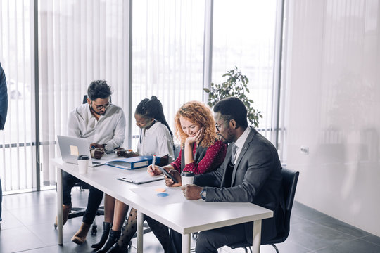 Relaxed informal IT business company meeting. Team leader in formal suit discussing new ways of vision and ideas of income increase with subordinates. Startup business and entrepreneurship concept