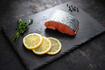 Surowy filet z łososia na czarnym kamieniu i ciemnym tle. © foodandcook