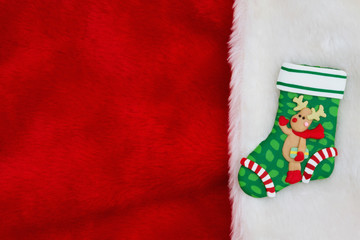 Obraz na płótnie Canvas Christmas stocking with a reindeer on red and white plush textured fabric background