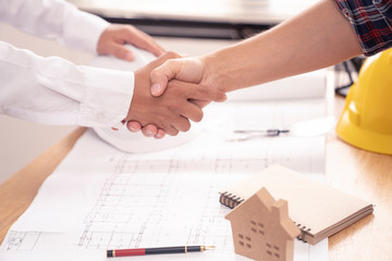 architect or civil engineer  and client or customer shaking hands for agreement of home or building plan,plan is fake only for stock photo.