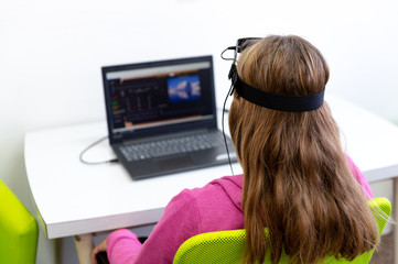 Young teenage girl during EEG neurofeedback session. Electroencephalography concept. Back view.